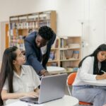 Students receiving guidance from a teacher in a well-equipped classroom.